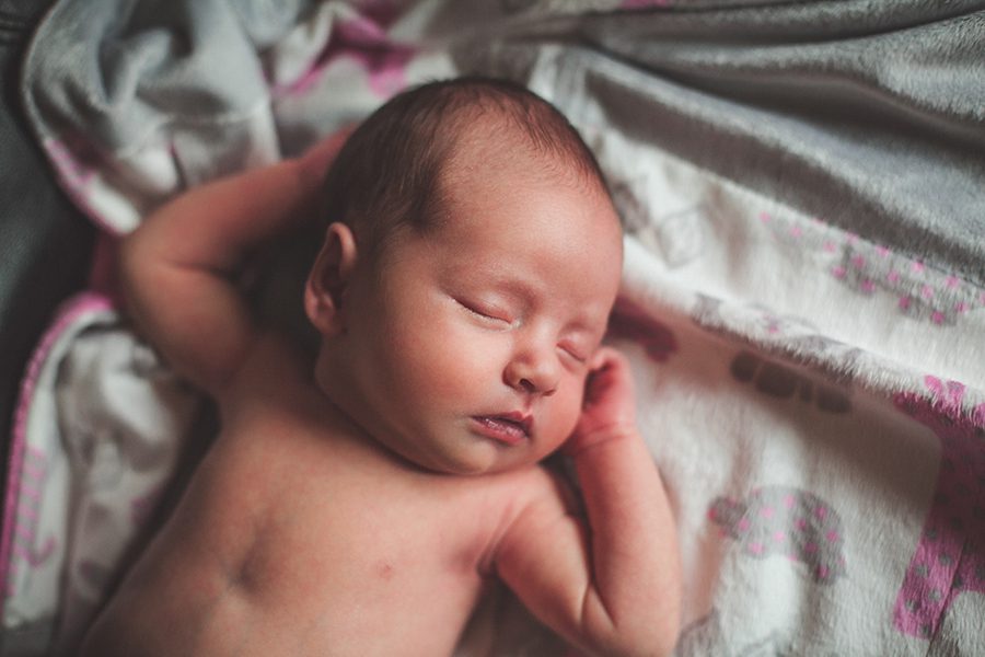 newborn lifestyle shoot on her pink and grey blanket