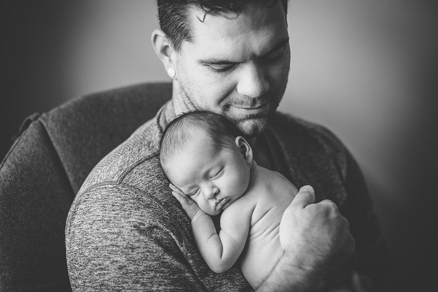 black and white close up of daddy holding newborn daughter on his shoulder