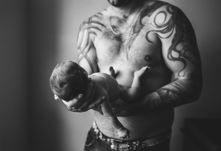daddy showing off tattoos with newborn baby