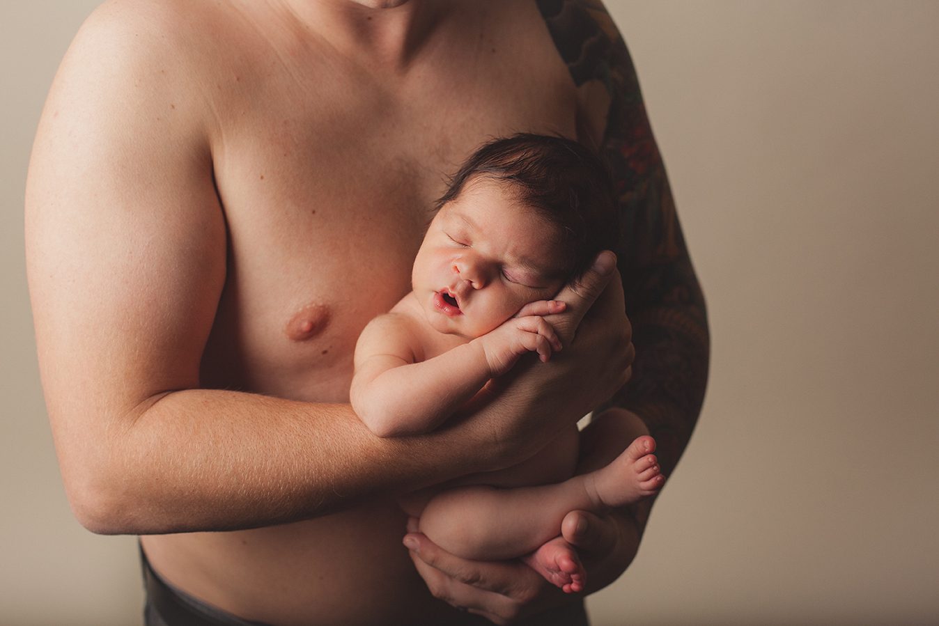 newborn boy posed on dads bare chest