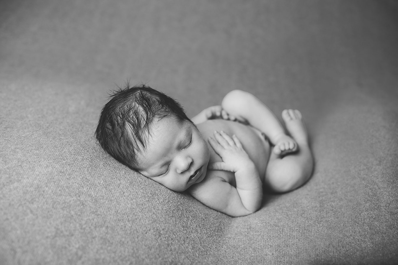newborn boy posed on back relaxing