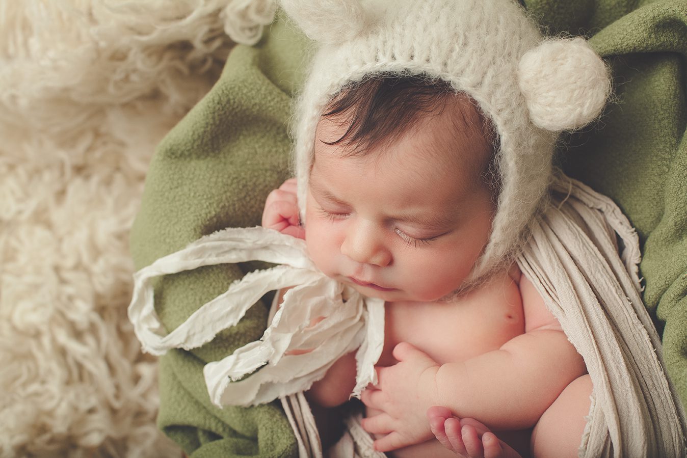 closeup of posed newborn photography with teddy bear ears