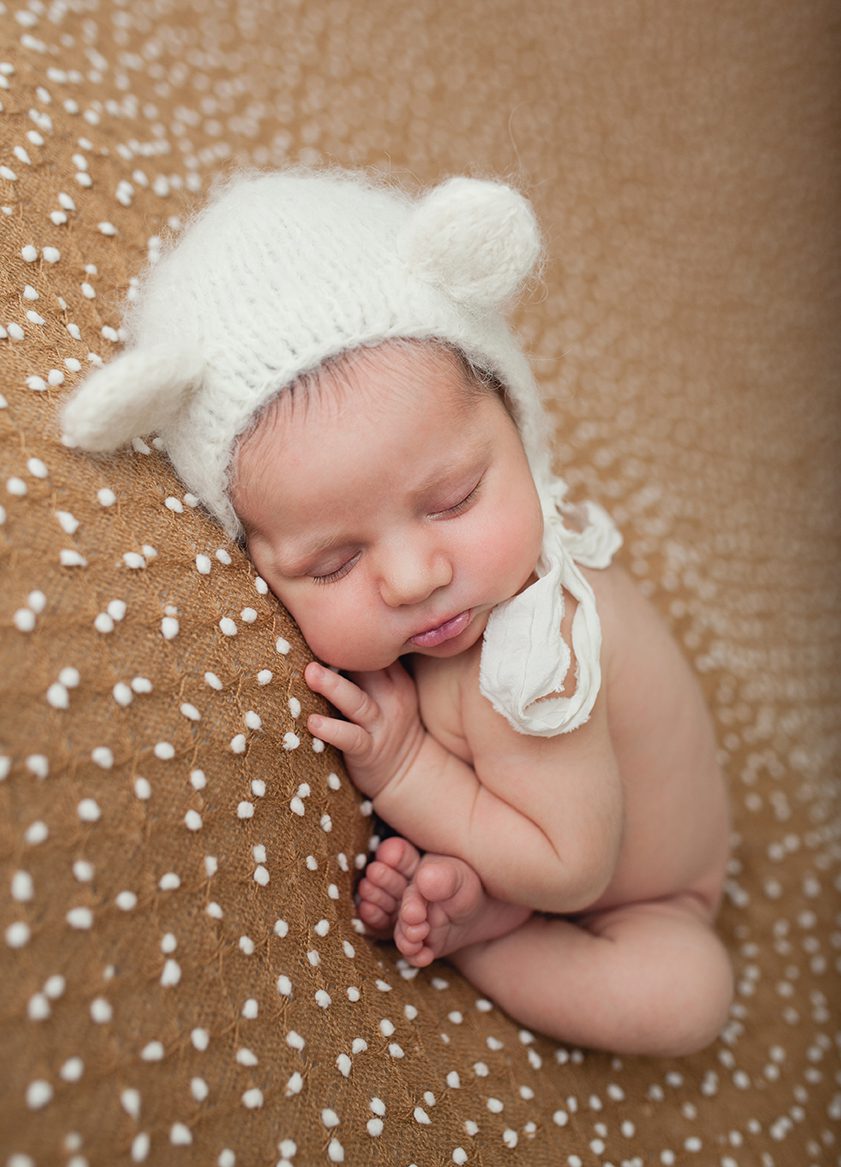 newborn taco pose or womb pose with teddy bear hat