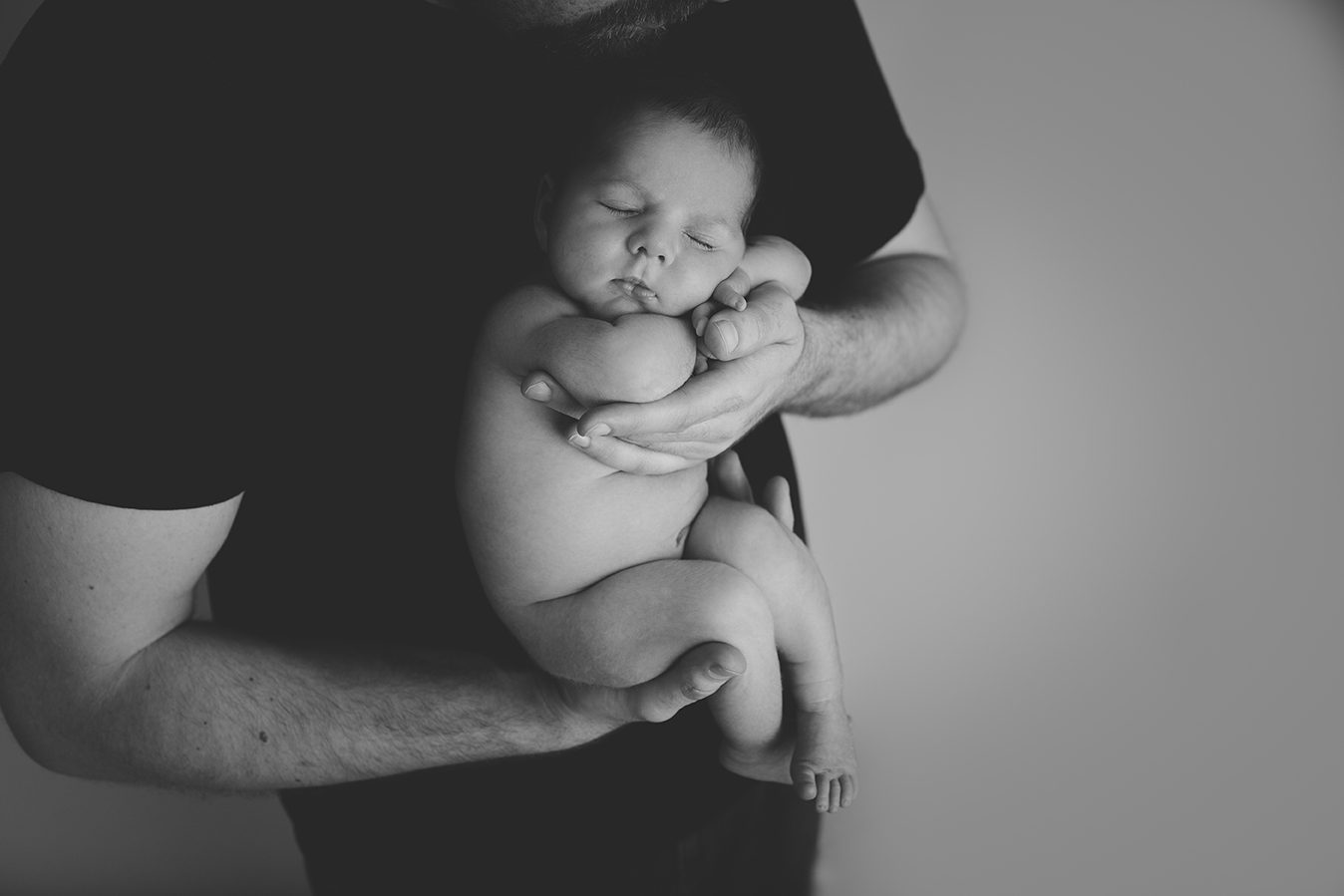 newborn posed in dads arms